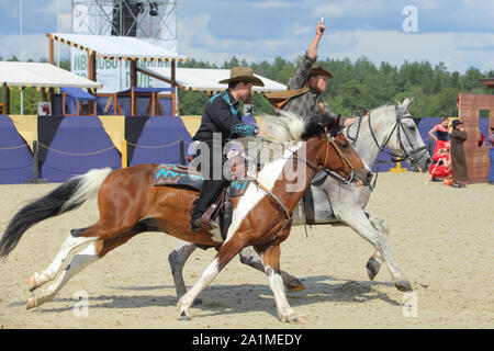 Montant un cheval de cow-boy au grand galop avec l'arme à la main Banque D'Images