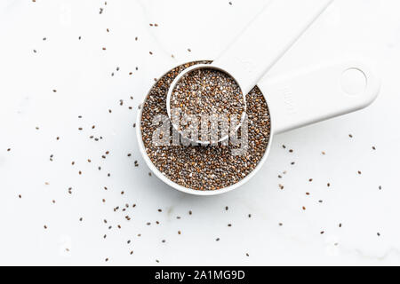Les graines de Chia sur scoop blanc sur fond blanc Banque D'Images