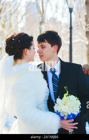 Jeune couple de nouveaux mariés marcher dans une forêt d'hiver dans la neige. Bride and Groom hugging dans le parc en hiver. Bel homme et de la femme de leur mariage Banque D'Images