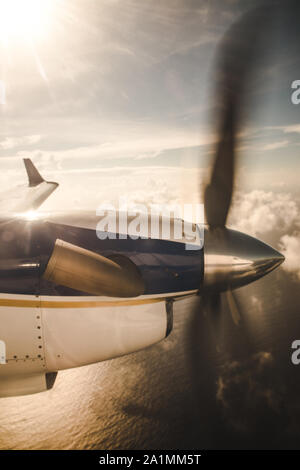 Petit avion de propulsion survolant les nuages vers une île de la mer des Caraïbes Banque D'Images