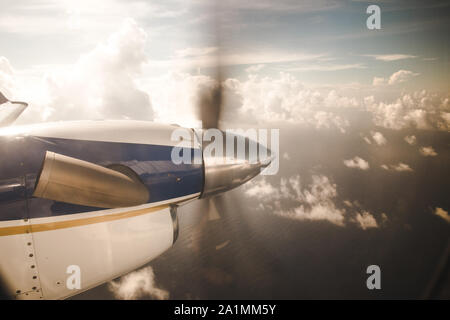 Petit avion de propulsion survolant les nuages vers une île de la mer des Caraïbes Banque D'Images