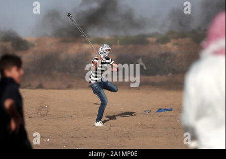 La bande de Gaza. 27 Sep, 2019. Un manifestant palestinien utilise une fronde pour lancer des pierres sur des soldats israéliens lors d'affrontements sur la frontière Gaza-Israel, à l'est du sud de la bande de Gaza ville de Khan Younis, 27 septembre 2019. Un jeune Palestinien a été tué vendredi par des tirs de l'armée israélienne au cours de l'hebdomadaire des manifestations anti-Israël le long de la frontière Gaza-Israel, ministère de la santé palestinien à Gaza a dit. Au moins 63 Palestiniens ont été blessés au cours d'une journée de protestation dans l'est de Gaza, Ashraf al-Qedra, porte-parole du ministère de la santé à Gaza, a dit. Credit : Yasser Qudih/Xinhua/Alamy Live News Banque D'Images