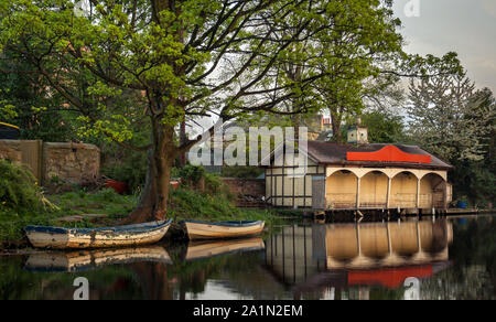 L'ancienne terrasse Ashley's Boathouse et deux barques sur une calme journée de printemps, avec des reflets dans l'eau et l'herbe verte et des arbres. Édimbourg. Scot Banque D'Images