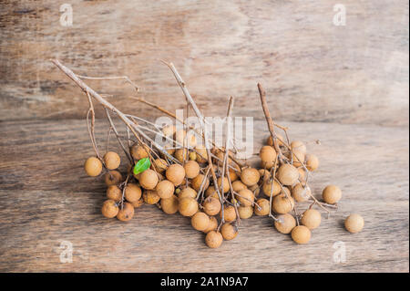 Longane Dmocarpus longane frais. Un bouquet de Longan et Peel montrent que la viande blanche avec des graines noires a été placée sur un fond en bois Banque D'Images