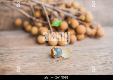 Longane Dmocarpus longane frais. Un bouquet de Longan et Peel montrent que la viande blanche avec des graines noires a été placée sur un fond en bois Banque D'Images