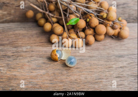 Longane Dmocarpus longane frais. Un bouquet de Longan et Peel montrent que la viande blanche avec des graines noires a été placée sur un fond en bois Banque D'Images