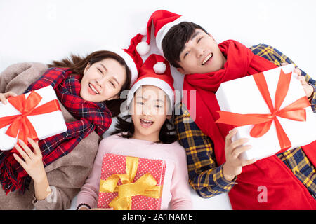Happy Family lying on floor et montrant cadeau de Noël Banque D'Images