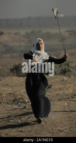 Gaza, la Palestine. 27 Sep, 2019. Un manifestant palestinien utilise une fronde pour lancer des pierres au cours d'une manifestation exigeant la fin de l'asphyxie siège sur la bande de Gaza pendant des années à la frontière Israel-Gaza clôture dans le sud de la bande de Gaza. Credit : SOPA/Alamy Images Limited Live News Banque D'Images