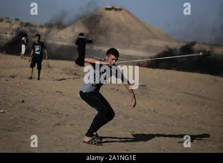 Gaza, la Palestine. 27 Sep, 2019. Un manifestant palestinien utilise une fronde pour lancer des pierres au cours d'une manifestation exigeant la fin de l'asphyxie siège sur la bande de Gaza pendant des années à la frontière Israel-Gaza clôture dans le sud de la bande de Gaza. Credit : SOPA/Alamy Images Limited Live News Banque D'Images