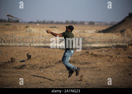 Gaza, la Palestine. 27 Sep, 2019. Un manifestant palestinien utilise une fronde pour lancer des pierres au cours d'une manifestation exigeant la fin de l'asphyxie siège sur la bande de Gaza pendant des années à la frontière Israel-Gaza clôture dans le sud de la bande de Gaza. Credit : SOPA/Alamy Images Limited Live News Banque D'Images