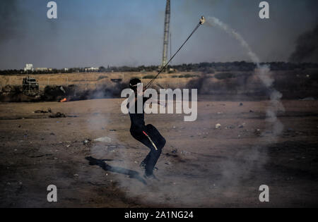Gaza, la Palestine. 27 Sep, 2019. Un manifestant palestinien utilise une fronde pour lancer des pierres au cours d'une manifestation exigeant la fin de l'asphyxie siège sur la bande de Gaza pendant des années à la frontière Israel-Gaza clôture dans le sud de la bande de Gaza. Credit : SOPA/Alamy Images Limited Live News Banque D'Images