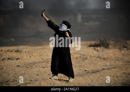 Gaza, la Palestine. 27 Sep, 2019. Un manifestant palestinien utilise une fronde pour lancer des pierres au cours d'une manifestation exigeant la fin de l'asphyxie siège sur la bande de Gaza pendant des années à la frontière Israel-Gaza clôture dans le sud de la bande de Gaza. Credit : SOPA/Alamy Images Limited Live News Banque D'Images