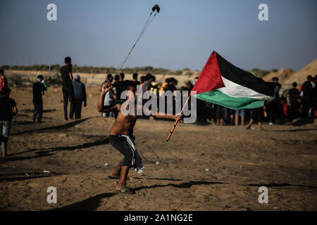Gaza, la Palestine. 27 Sep, 2019. Un manifestant palestinien utilise une fronde pour lancer des pierres au cours d'une manifestation exigeant la fin de l'asphyxie siège sur la bande de Gaza pendant des années à la frontière Israel-Gaza clôture dans le sud de la bande de Gaza. Credit : SOPA/Alamy Images Limited Live News Banque D'Images