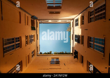 Concept de quarantaine. Vue du ciel bleu du bas vers le haut à l'intérieur d'une petite cour d'une ancienne maison en Italie Banque D'Images