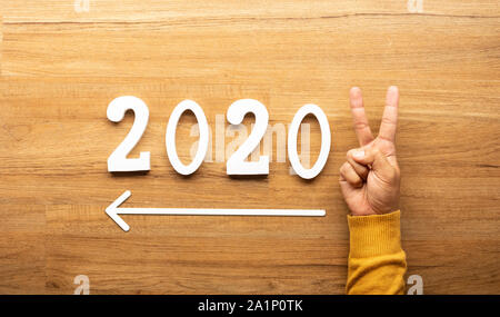 2020 Nouvel an fête concepts avec texte numéro et main humaine montrant V signe sur fond de bois. d'inspiration et de motivation idées Banque D'Images