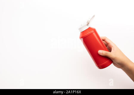 Serrant la main Youngwoman bouteille de sauce tomate ketchup sur fond blanc.Restauration rapide et saine des idées concepts Banque D'Images