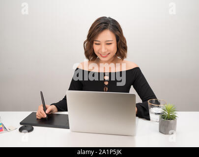 Jeune femme d'origine asiatique concepteur à l'aide de tablette graphique tout en travaillant avec l'ordinateur Banque D'Images