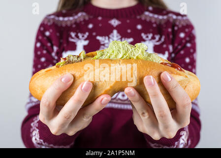 La mauvaise alimentation food concept. Cropped photo gros plan de happy smiling adolescent excité holding large sandwich dans les mains essayant de faire deux moitiés isol Banque D'Images