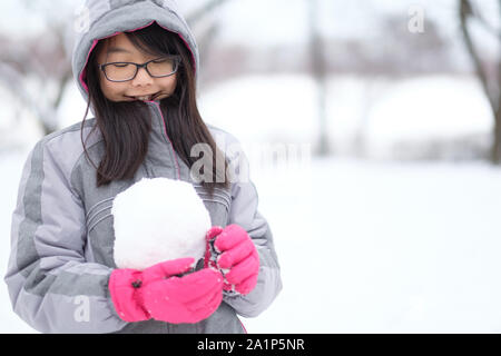 Portrait of Asian teen tenant une boule de neige en mains Banque D'Images