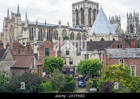 Flèches et toit de la cathédrale York Minster, UK, en arrière-plan, s'élevant au-dessus de toits de bâtiments originaux, vu contre ciel nuageux. Banque D'Images