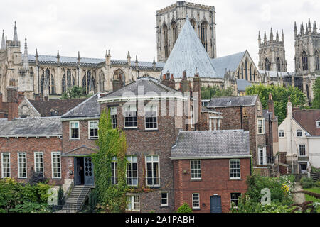 Flèches et toit de la cathédrale York Minster, UK, en arrière-plan, s'élevant au-dessus de toits de bâtiments originaux, vu contre ciel nuageux. Banque D'Images