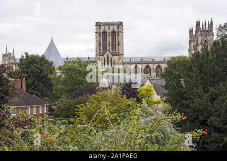 Flèches et toit de la cathédrale York Minster, UK, en arrière-plan, s'élevant au-dessus de toits de bâtiments originaux, vu contre ciel nuageux. Banque D'Images