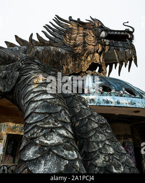 Immense et effrayant dragon en pierre de pointes et bouche ouverte avec dents d'en bas en grand angle au parc aquatique abandonné, Thuy Tien lake, Hue, Vietnam Banque D'Images