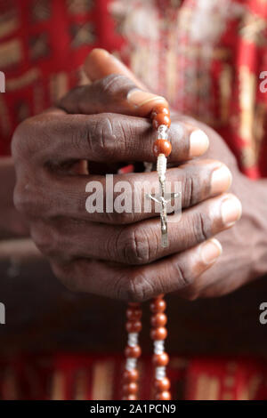 Africain priant dans une église avec un chapelet. Banque D'Images