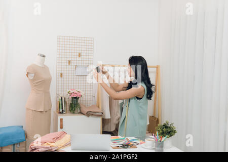 Jeune femme d'origine asiatique créateur de mode de prise de mesures sur mannequin in her Studio Banque D'Images