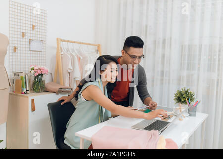 L'équipe de designers de mode croquis, axé sur l'homme et la femme la collaboration sur de nouveaux vêtements de travail couleur choix création de collections avec swatche