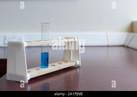 Sol en bois porte-tubes à essai avec tube à essai de la solution de sulfate de cuivre dans une ancienne école laboratoire de sciences. L'éducation scientifique lab concept Banque D'Images