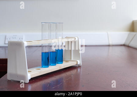 Sol en bois porte-tubes à essai avec tube à essai de la solution de sulfate de cuivre dans une ancienne école laboratoire de sciences. L'éducation scientifique lab concept Banque D'Images