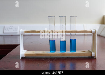 Sol en bois porte-tubes à essai avec tube à essai de la solution de sulfate de cuivre dans une ancienne école laboratoire de sciences. L'éducation scientifique lab concept Banque D'Images