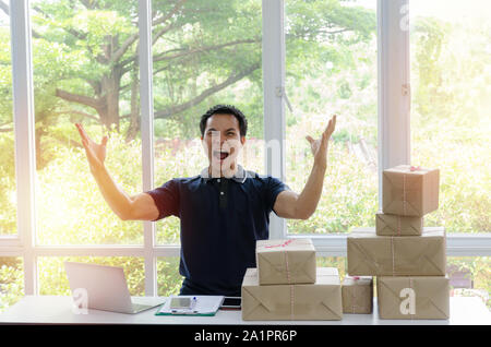 Démarrage. asian man heureux après nouvelle commande d'un client avec ordinateur portable, téléphone portable, l'emballage de livraison fort sur la table, propriétaire de petite entreprise Banque D'Images