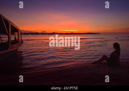 Jeune femme de détente sur la plage de Gili Meno. Gili Trawangan, vu de l'Gili Meno avec le Mont Agung en arrière-plan, Bali Indonésie après soleil Banque D'Images