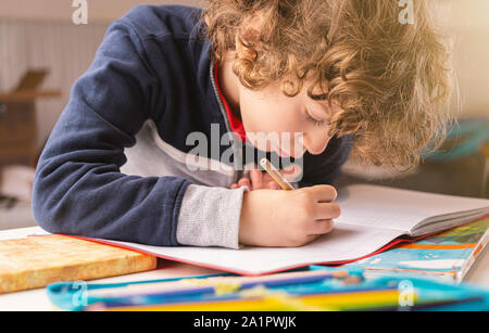 Cute kid écrit sur un cahier dans sa maison. Vie de l'école élémentaire de personnes concept Banque D'Images