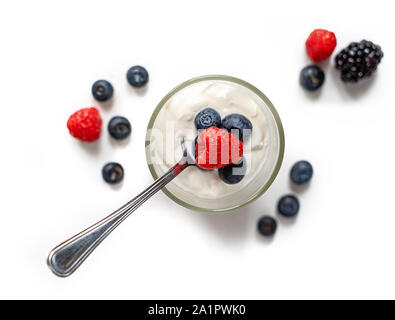 Un verre rempli de yaourt aux fruits rouges et une cuillère isolé sur un fond blanc, pur. Profondeur de champ libre. Banque D'Images