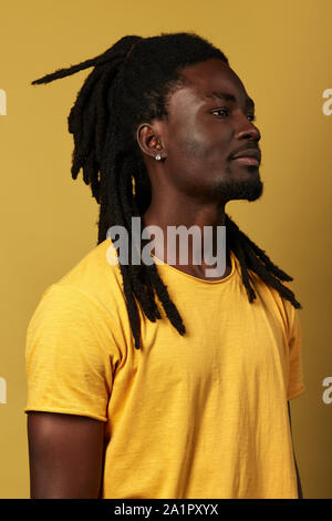 Profil de bel homme sérieux avec des cheveux à la distance. close up side view portrait isolé sur fond jaune. Banque D'Images