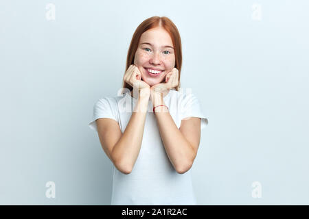 Étudiants féminins positifs est titulaire d'chin, a expression positive, ouvre les yeux, sourire agréable, isolé sur fond blanc.close up portrait of positive, fe Banque D'Images