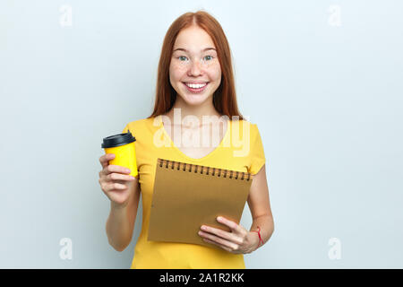 Cheerful girl détient café à emporter et copie d'adresses, étudiant a briser après la tenue d'une conférence. portrait, isolé sur fond blanc, studio sh Banque D'Images