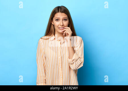 Inquiet frustré woman looks nerveusement, piqûres d'ongles, montres horror film strilling en mouvement. Soucis d'étudiants excités nerveux avant les examens, isol Banque D'Images