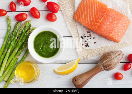 Filet de saumon frais, sauce pesto, tomates cerise, citron, huile d'olive et d'asperges. Ingrédients saumon en papillote au four fo avec le pesto et légumes Banque D'Images