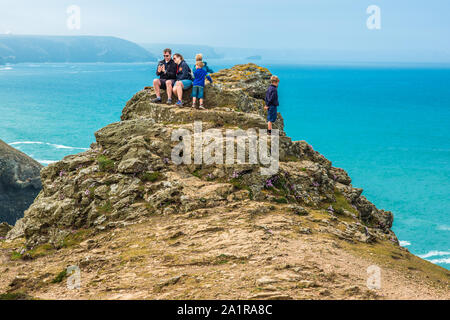 Une famille sur les rochers au-dessus de la Chapelle Sainte Agnès Porth Littoral du patrimoine à Cornwall, Angleterre, Royaume-Uni. Banque D'Images