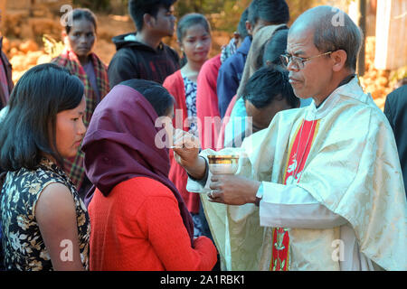 Prêtre catholique donne à la Communion, l'Eucharistie catholique au cours d'une messe du dimanche pour les gens de la tribu Khasi ethniques dans le village de Jarain Khasi Hills, dans l'état de Meghalaya, en Inde Banque D'Images