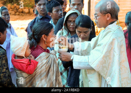 Prêtre catholique donne à la Communion, l'Eucharistie catholique au cours d'une messe du dimanche pour les gens de la tribu Khasi ethniques dans le village de Jarain Khasi Hills, dans l'état de Meghalaya, en Inde Banque D'Images