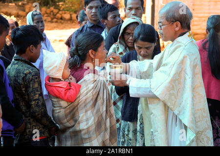 Prêtre catholique donne à la Communion, l'Eucharistie catholique au cours d'une messe du dimanche pour les gens de la tribu Khasi ethniques dans le village de Jarain Khasi Hills, dans l'état de Meghalaya, en Inde Banque D'Images