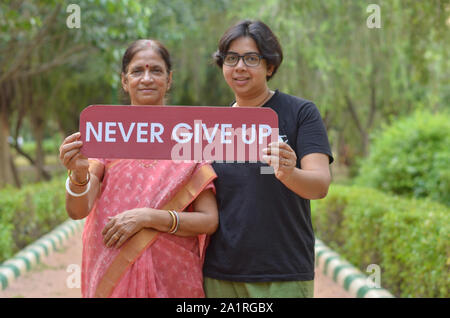 Bengali Senior femme indienne avec sa jeune fille tenant une pancarte avec le message "ne jamais abandonner" dans un parc à New Delhi, Inde Banque D'Images