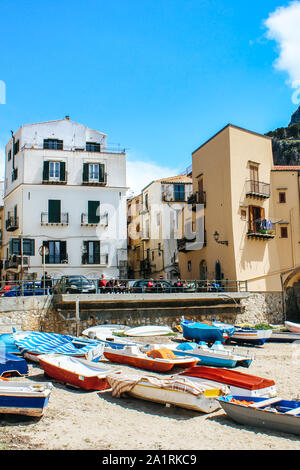 Cefalu, Sicile, Italie - Apr 7, 2019 : beau vieux port dans le petit village sicilien. Les bateaux de pêcheurs sur une plage de sable. Maisons traditionnelles, montagne en arrière-plan. Les gens sur la promenade. Banque D'Images