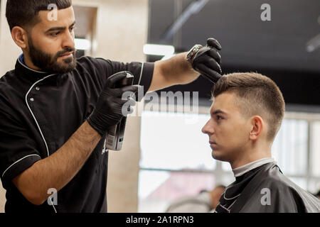 Guy brutale dans un salon de coiffure moderne. Coiffure coiffure rend un homme . Coiffure coiffure avec maître n'tondeuse à cheveux. Concept de coiffure Banque D'Images