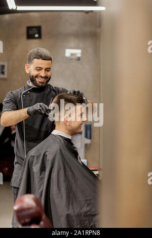 Guy brutale dans un salon de coiffure moderne. Coiffure coiffure rend un homme . Coiffure coiffure avec maître n'tondeuse à cheveux. Concept de coiffure Banque D'Images